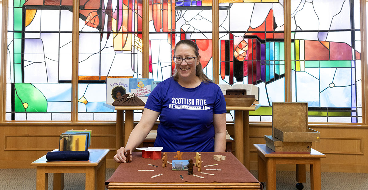 Full-time chaplain Jerilynn Putnam smiles with figurines, showcasing godly play.