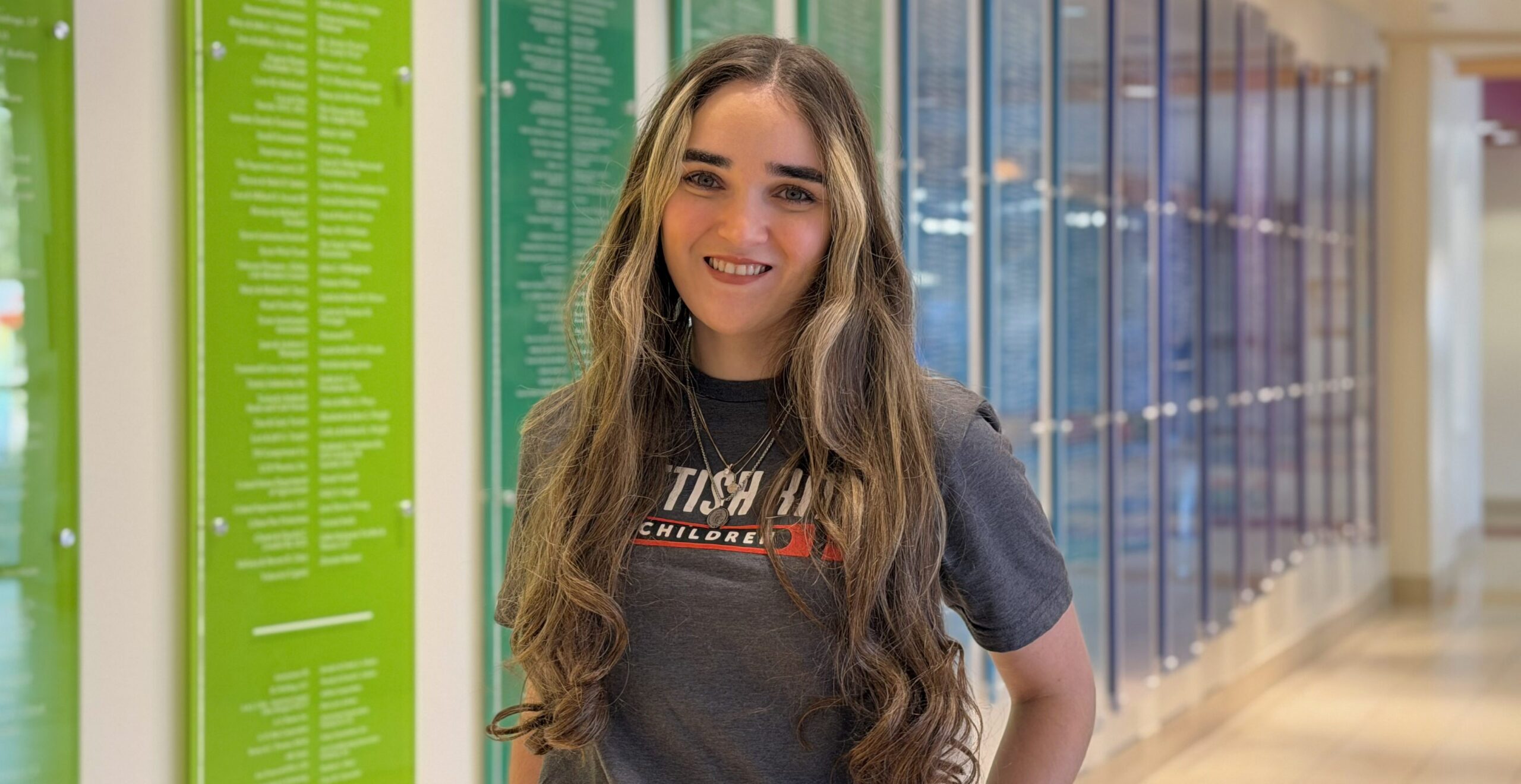 Registered dietitian poses in front of Scottish Rite for Children's donor wall.
