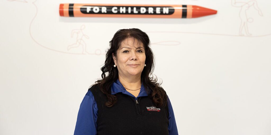 Lidia Quintero in front of the Scottish Rite for Children logo.