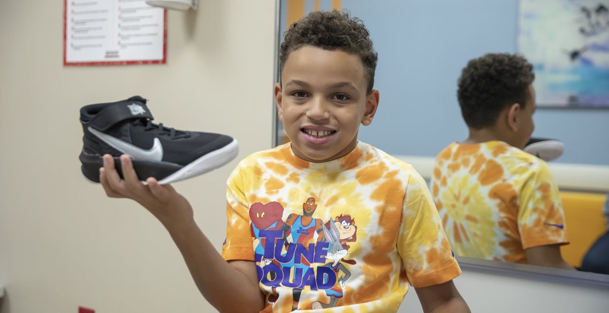 Shoe-blog Patient, Caden, holding Nike shoes with Zippers