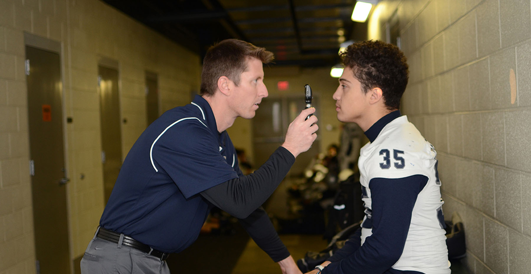 Miller AT Nimitz concussion locker room assessment and balance testing #35 >12y Miller in football tunnel doing head exam