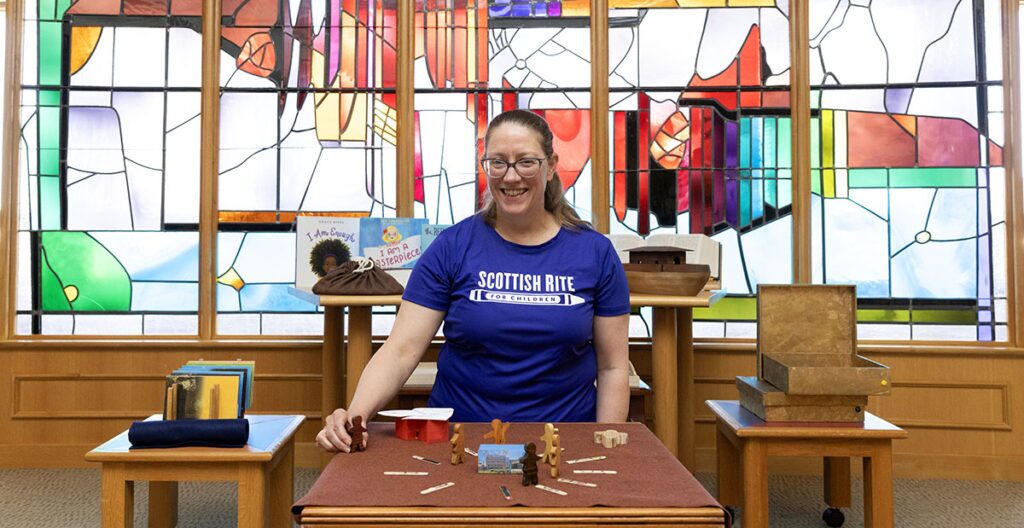 Full-time chaplain Jerilynn Putnam smiles with figurines, showcasing godly play.
