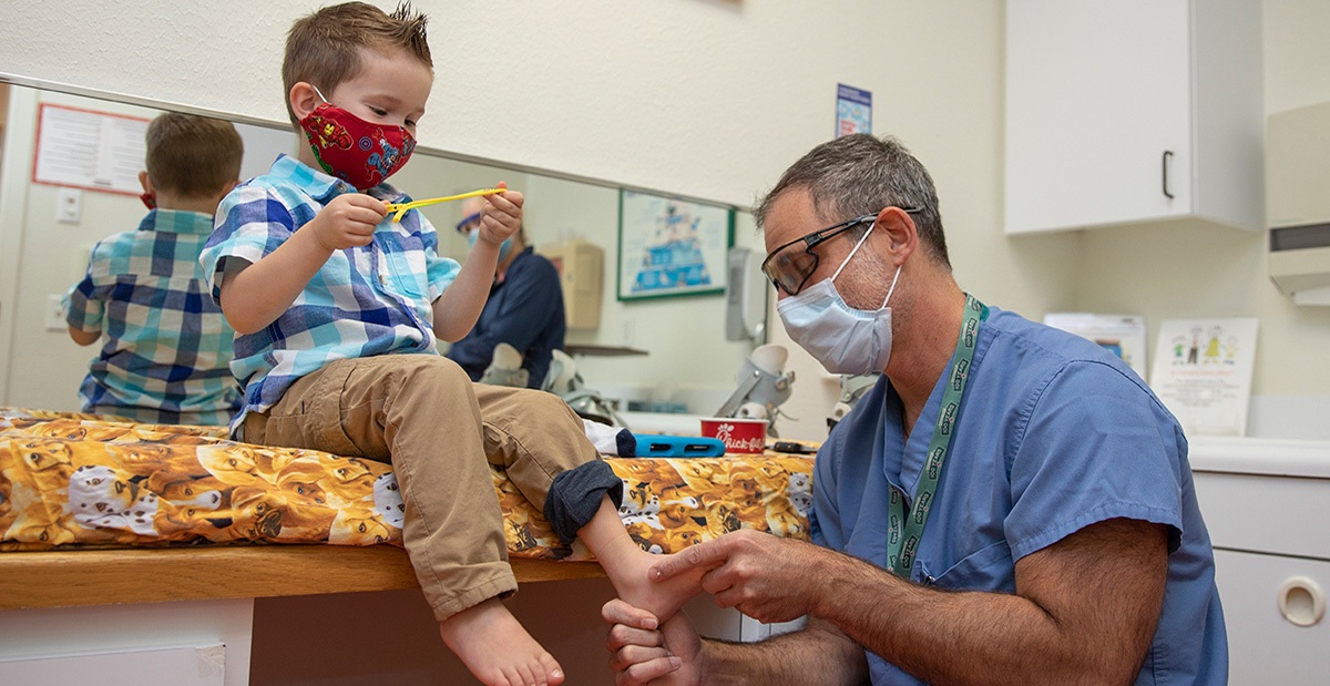 A boy wearing a red mask is being examined by a doctor