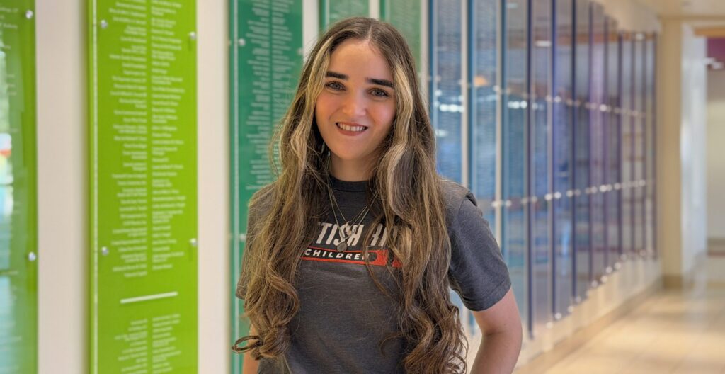 Registered dietitian poses in front of Scottish Rite for Children's donor wall.